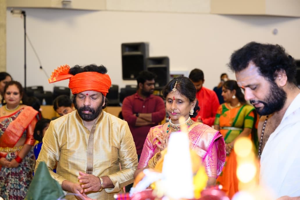 Community members in silk sarees and a saffron turban with folded hands during the pooja at KCTCA's Bathukamma 2024
